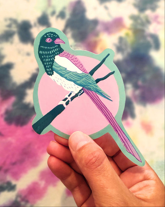Hand holding a colorful bird-shaped sticker against a tie-dye background