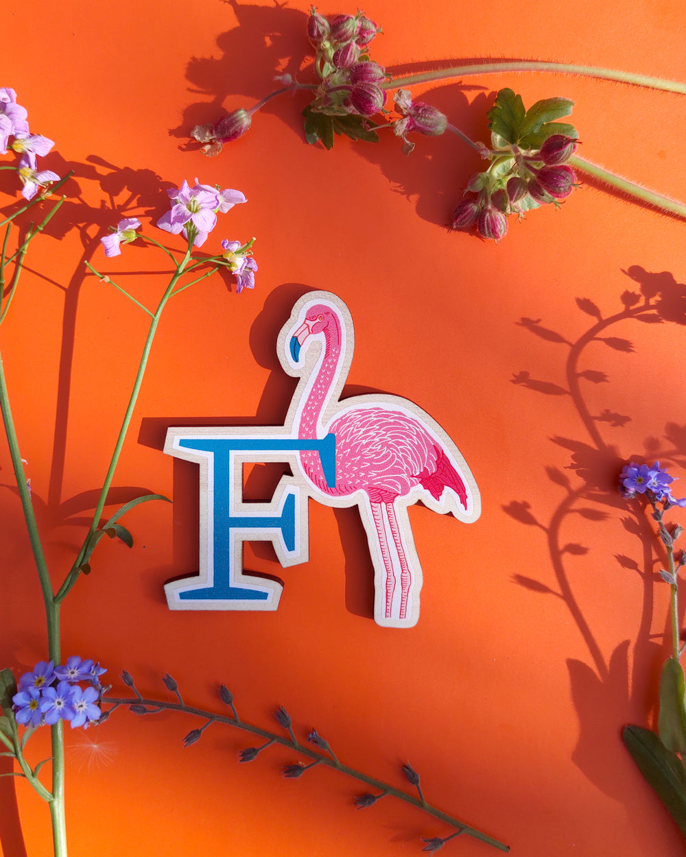 Flamingo-shaped letter 'F' on an orange background with flowers