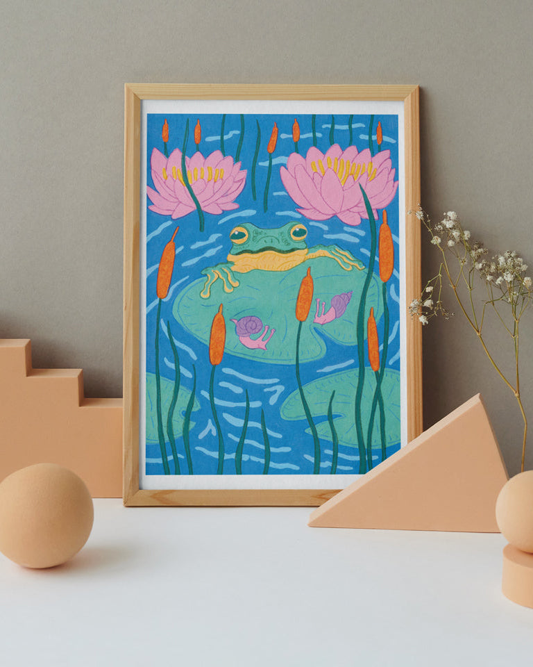 Framed artwork of a frog and lilies on a neutral background with geometric shapes.
